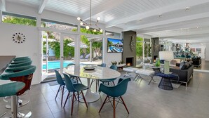 A spacious living area with a pool, modern furniture, and a large TV screen. - Iconic Twin Palms - Classic Upscale Midcentury! (Palm Springs)