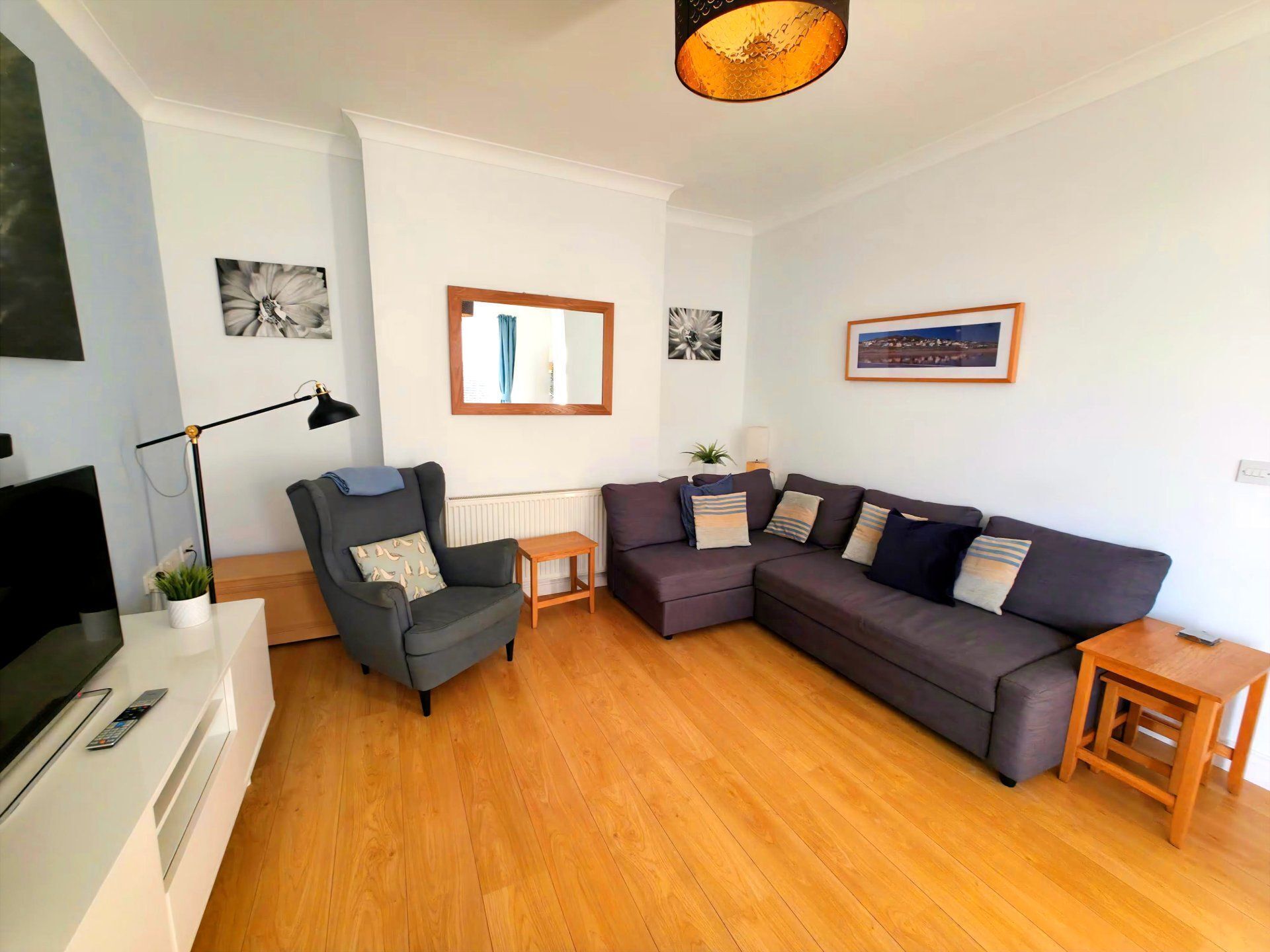 A modern living room with a grey sofa, a black armchair, a wooden coffee table, and a TV on a white stand.