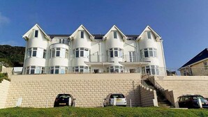 A large, multi-story building with a symmetrical facade, featuring multiple balconies and a central staircase leading to the upper levels.