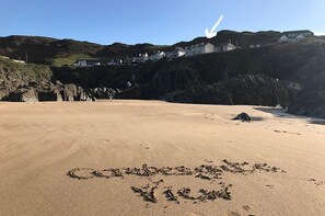 A sandy beach with footprints and a circle drawn on the sand.