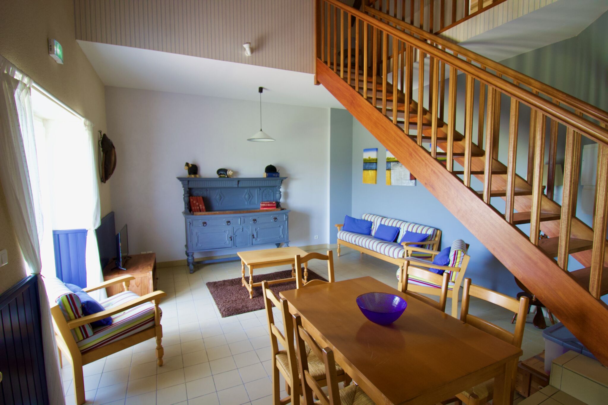 A dining area with wooden furniture, a staircase, and a blue cabinet.