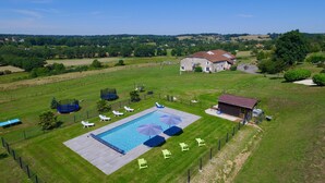 An aerial view of a property with a swimming pool, sun loungers, and a large stone building.
