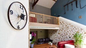 A spacious living area with a wooden dining table, red sofa, and a clock on the wall.