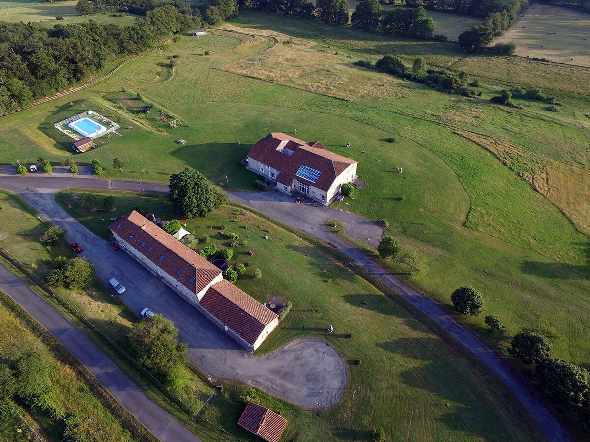 An aerial view of a property with two main buildings, a swimming pool, and a road.