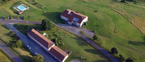 An aerial view of a property with two main buildings, a swimming pool, and a road.