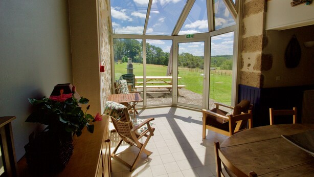 A room with a large glass door leading outside, wooden furniture, and a potted plant.