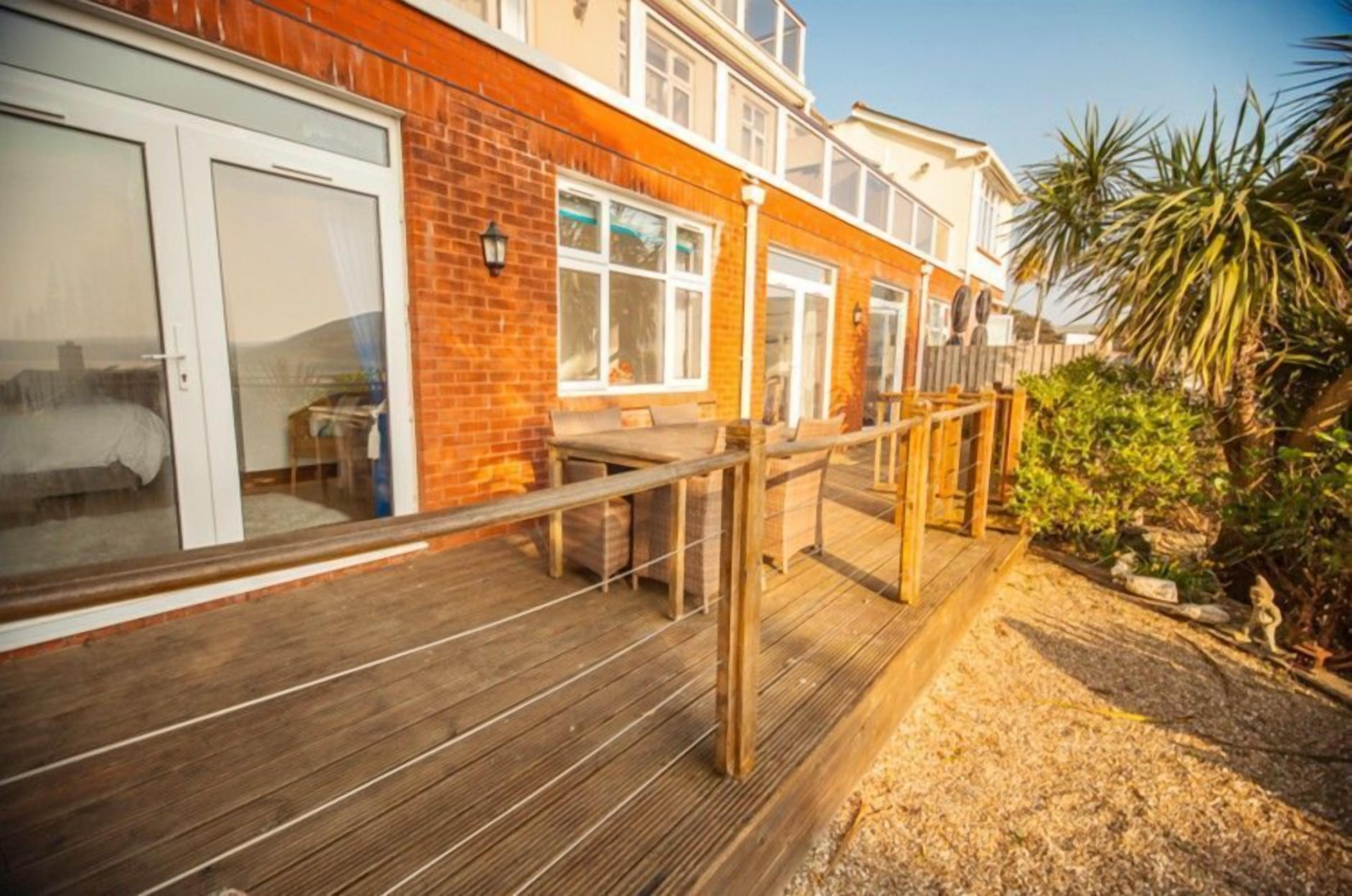 A wooden deck with a railing, a brick wall, and a clear sky.