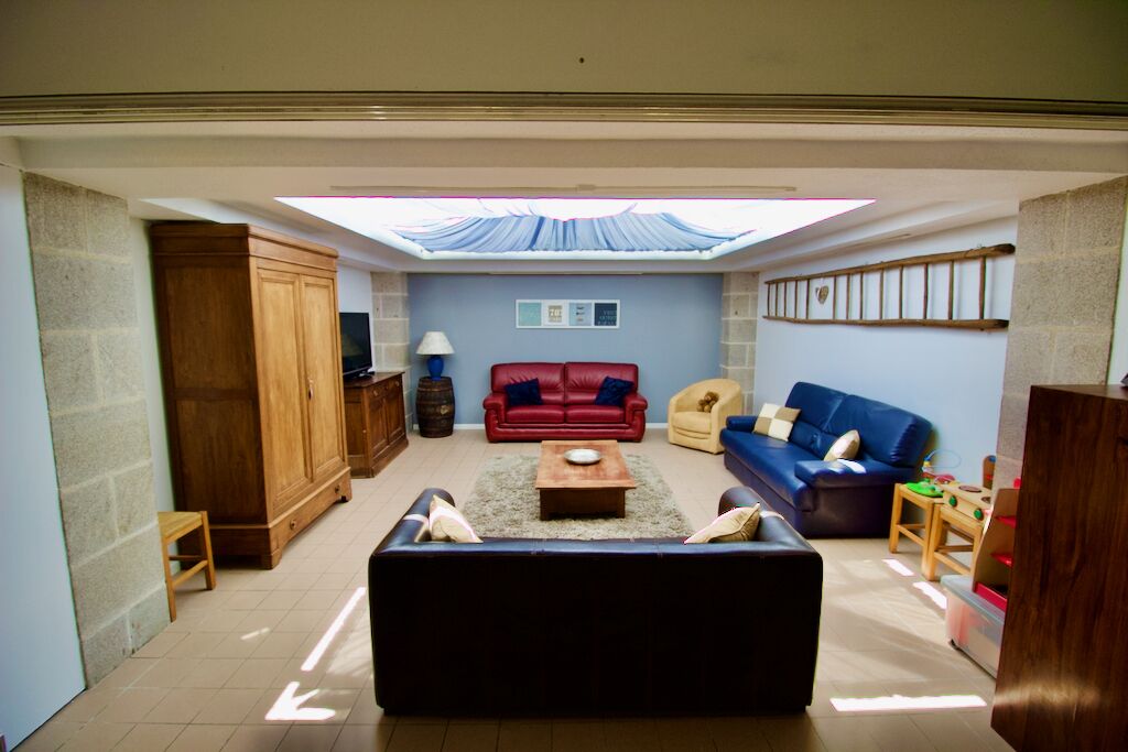 A living room with a skylight, a red sofa, a blue sofa, a wooden cabinet, and a small table with toys.