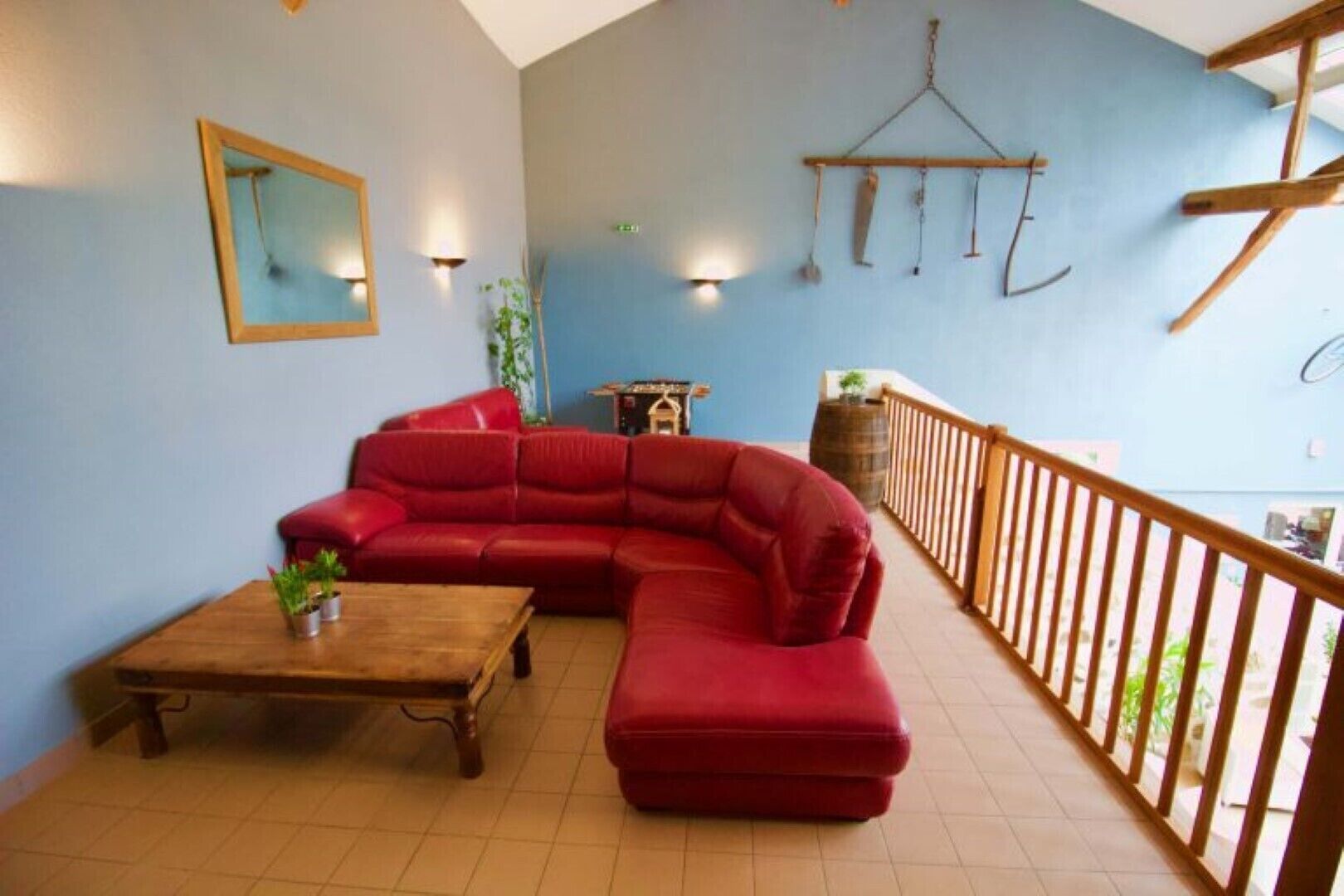 A living room with a red sectional sofa, a wooden coffee table, and a hanging light fixture.