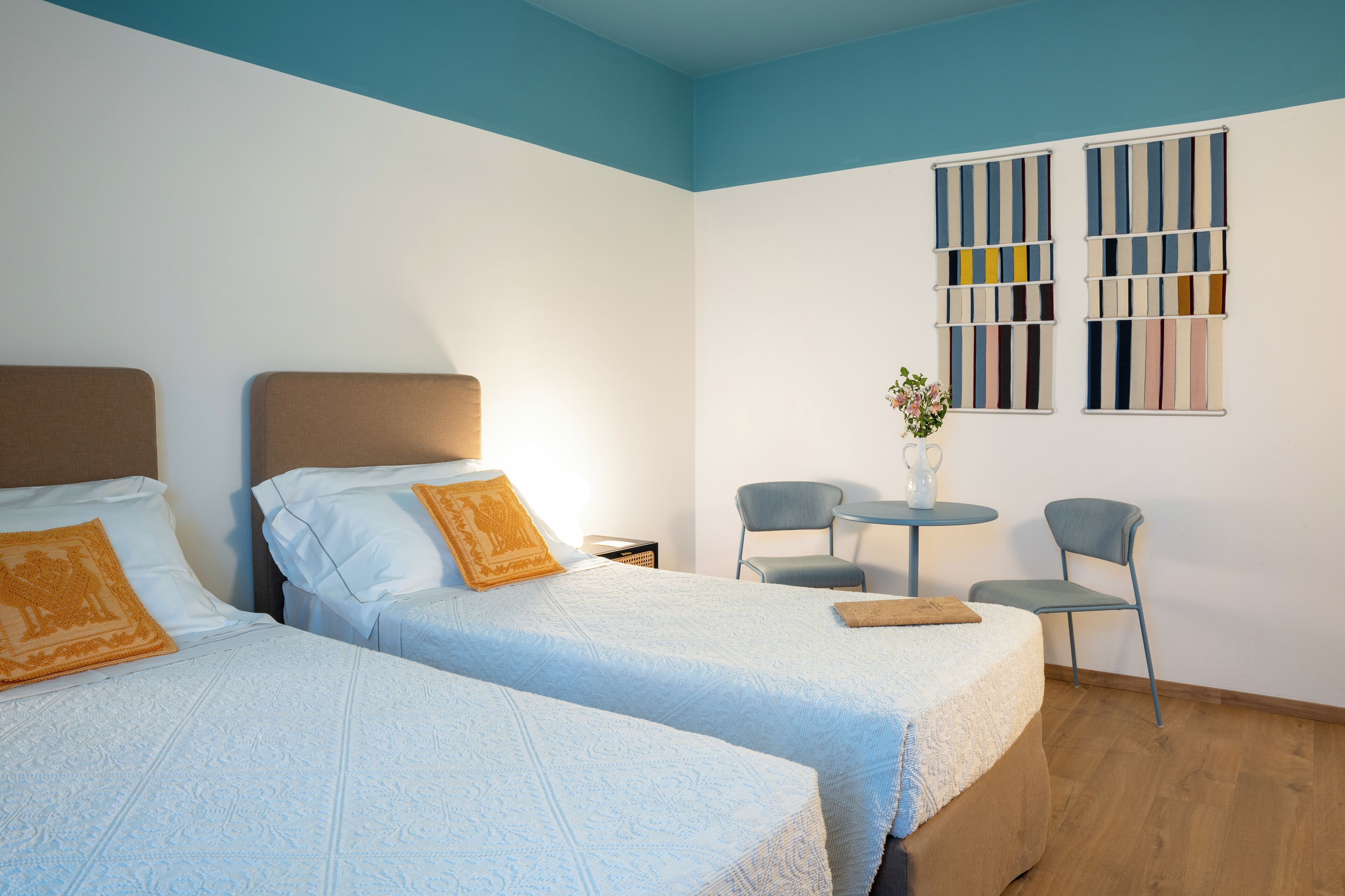 A hotel room with two beds, a small table, two chairs, and a wall-mounted TV.