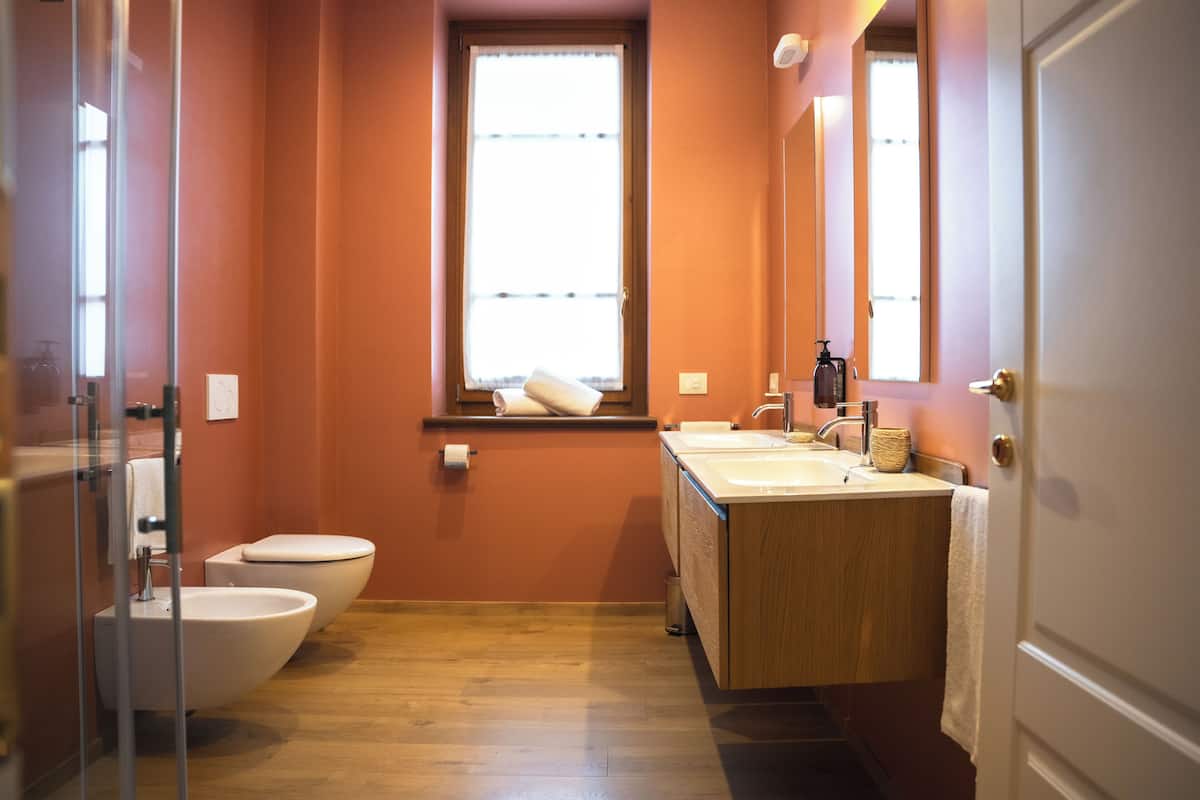 A bathroom with two toilets, a sink, and a window.