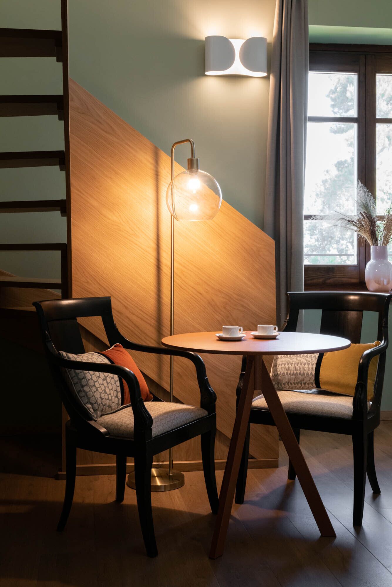 Ein gemütlicher Sitzbereich mit zwei Sesseln, einem kleinen runden Tisch und einer Stehlampe.