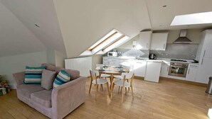 Un appartement de style loft comprenant un coin repas, une kitchenette et un canapé avec des coussins à rayures.