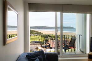 A balcony with a view of the beach and hills.