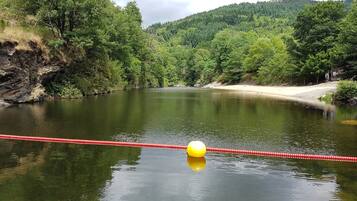 A calm river with a red rope barrier and a yellow buoy in the foreground.