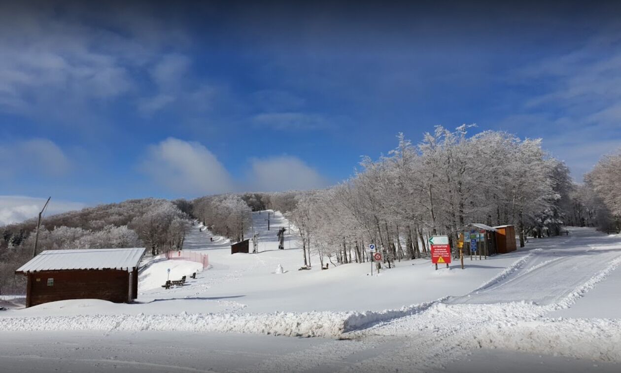 Un paysage enneigé avec une piste de ski, un petit bâtiment et un panneau indicateur.