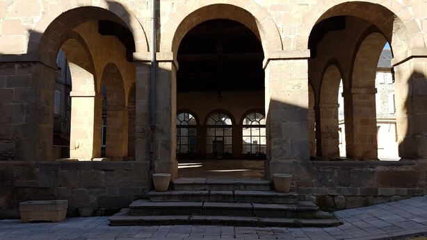 A stone building with three large arches and a staircase leading to a covered area. - Studio in the heart of the village (Saint-Jean-du-Bruel)