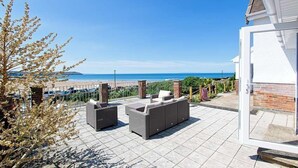 Un patio con muebles exteriores con vista a la playa.