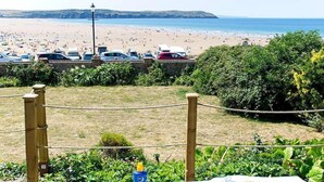 Vista de la playa con coches aparcados y una valla.