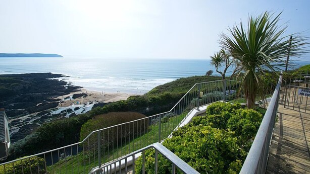A coastal view from a balcony with a private access sign, overlooking a beach and ocean.