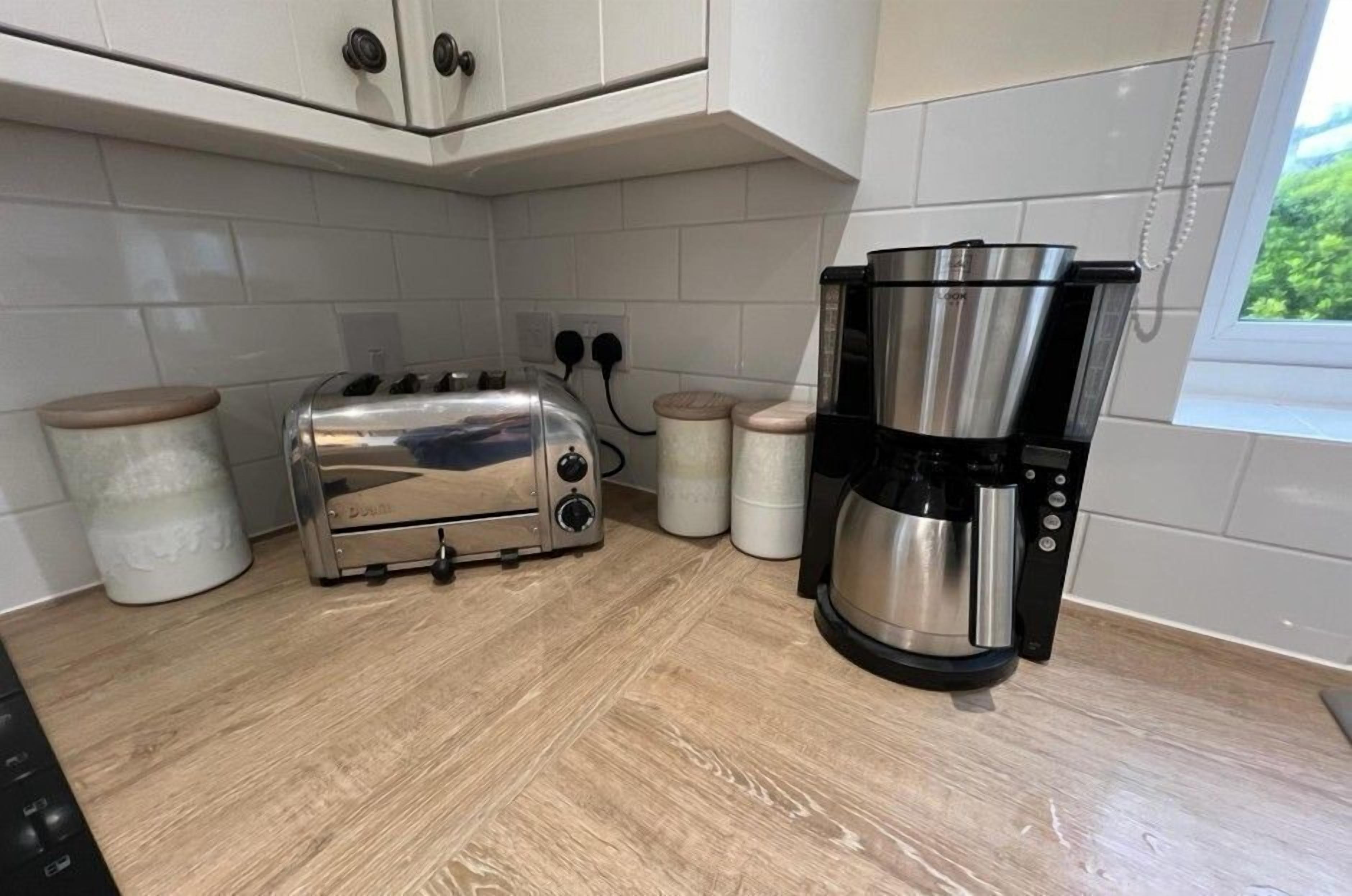 A kitchen with a toaster, a coffee maker, and two containers on the counter.