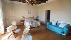 A bedroom with a bed, a chair, a sofa, a table, and a chandelier. - -Upper Room- (launay blot)