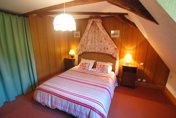 A bedroom with a bed, two bedside tables, a canopy bed, wooden walls, and a green curtain.