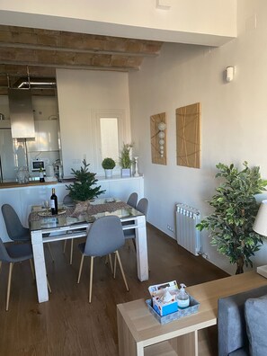 A modern kitchen with a built-in oven and microwave, a dining area with a glass table and chairs, and a living room with a sofa and a lamp. - Corsini & Friends a paradise in the center of Tarragona (Tarragona)