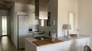 A modern kitchen with white cabinetry, a stainless steel refrigerator, a microwave, and a sink. - Corsini & Friends a paradise in the center of Tarragona (Tarragona)