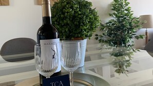 A table with a wine bottle and two glasses, a small potted plant, and a wall with a geometric tapestry. - Corsini & Friends a paradise in the center of Tarragona (Tarragona)