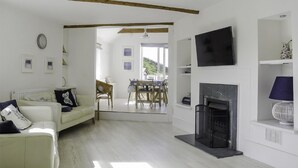 Ein Wohnzimmer mit Kamin, einem an der Wand befestigten Fernseher und einem Essbereich mit Tisch und Stühlen.