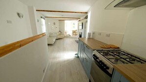 Eine schmale Küche mit einem Gaskochfeld und Holzschränken.