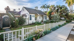 A residential property with a white picket fence, a well-maintained garden, and a clear sky. - Refined Coastal Escape a Block from West Beach! (Santa Barbara)