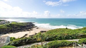 A coastal landscape with a beach, rocky shoreline, and greenery. - Fabulous 3 bed apartment with amazing seaviews and balcony (Woolacombe)