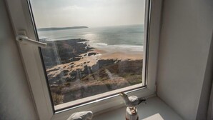A window with a view of a beach and rocky coastline. - Fabulous 3 bed apartment with amazing seaviews and balcony (Woolacombe)