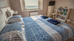 A bedroom with a bed, a bookshelf, a chair, and a window with a view. - Fabulous 3 bed apartment with amazing seaviews and balcony (Woolacombe)