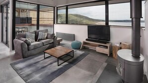 Ein modernes Wohnzimmer mit Sofa, Couchtisch, Fernseher und Kaminofen.