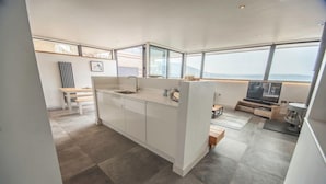 Eine moderne Küche mit einer großen Kochinsel, einem Essbereich mit einer Bank und einem Fernseher.