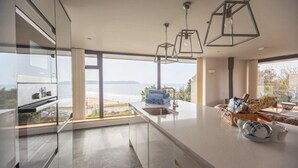 Una cocina moderna con una isla grande, vistas al mar y un comedor.