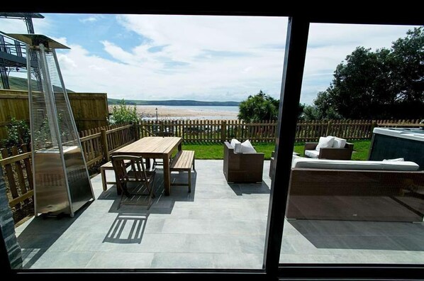 An outdoor patio with a wooden table and chairs, a sofa, and a grill. - A simply stunning 3 bedroom apartment overlooking Woolacombe beach with hot tub! (Woolacombe)