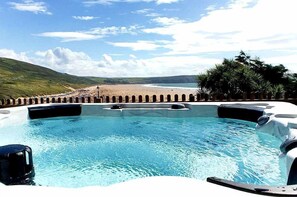 A swimming pool with a view of a beach and hills. - A simply stunning 3 bedroom apartment overlooking Woolacombe beach with hot tub! (Woolacombe)