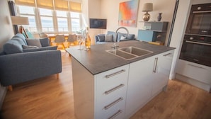 Eine moderne Küche mit einer zentralen Kochinsel, weißen Schränken und einem eingebauten Backofen.