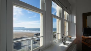 Ein Zimmer mit großen Fenstern und Blick auf Strand und Meer.