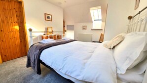 Ein Schlafzimmer mit einem Bett, einer Holztür, einem Heizkörper, einem Fenster und einem Stuhl.
