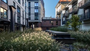 A modern urban courtyard with a mix of residential buildings, a small bridge, and lush greenery.