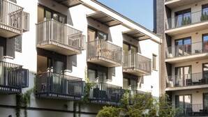 A multi-story residential building with balconies, large windows, and a flat roof.