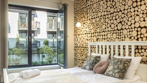 A bedroom with a bed, pillows, and a view of a balcony.