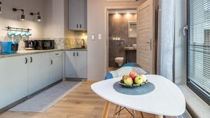 A compact kitchen with modern appliances, a dining area with a table and chairs, and a view of the adjacent bathroom.