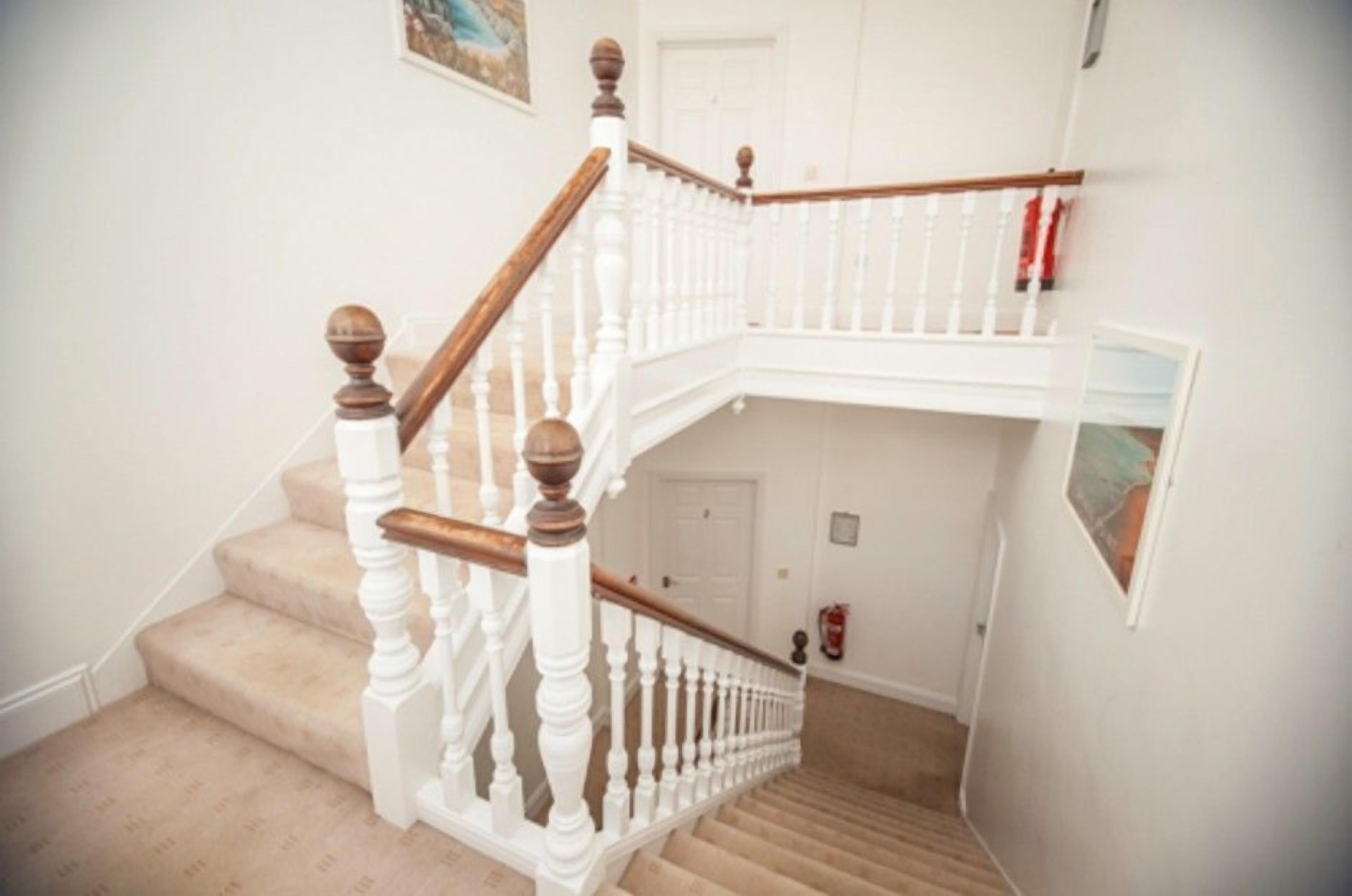 A staircase with white balusters and wooden handrails, leading to an upper floor.