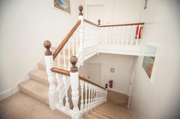 A staircase with white balusters and wooden handrails, leading to an upper floor.